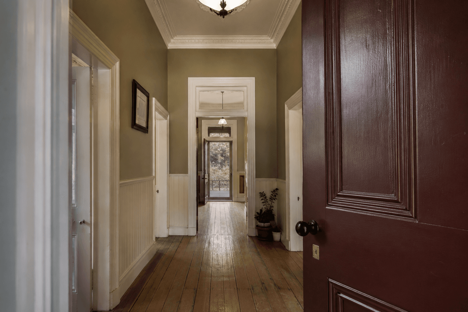 Heritage hallway with cream walls, timber trim and a burgundy front door